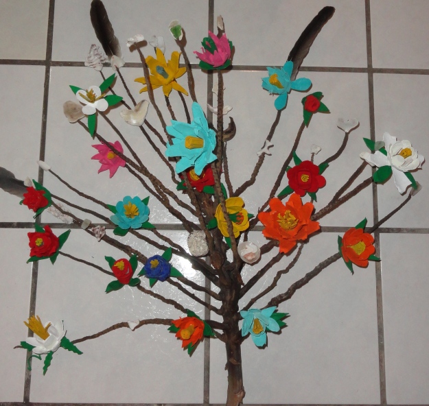It started with a palm fruiting stem washed ashore.  I added flowers I made of cutouts from egg cartons, painted and glued together, then added pelican feathers and verious heart-shaped shells and small stones found on beach walks. 